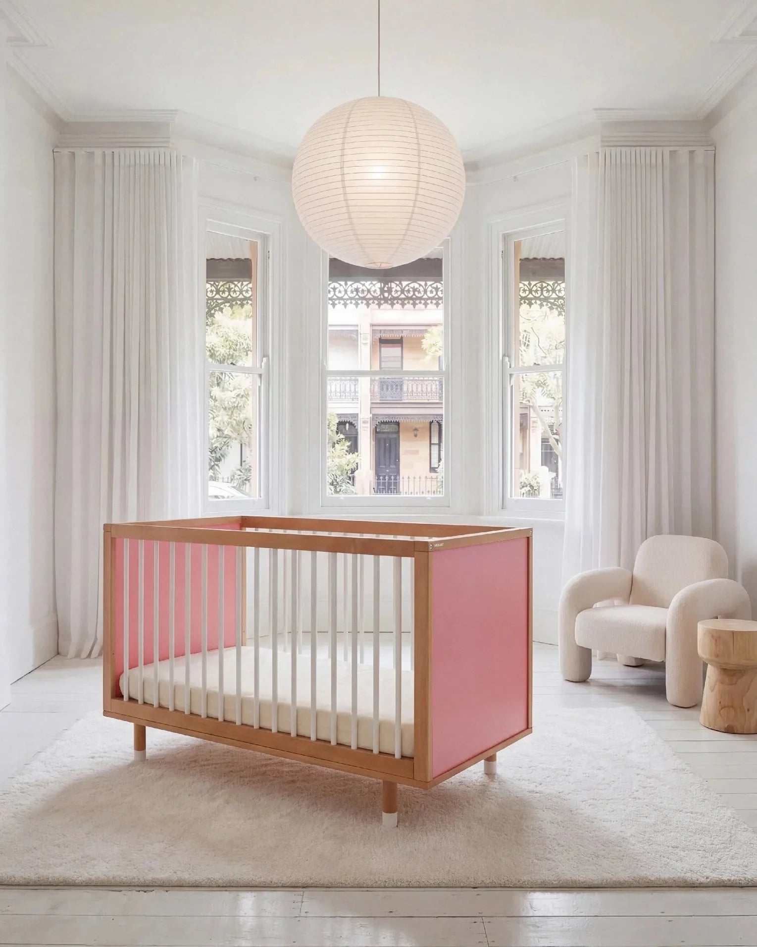 Bold Baby Cot in Pink and Red colourway, front three-quarter view showing the pink panel