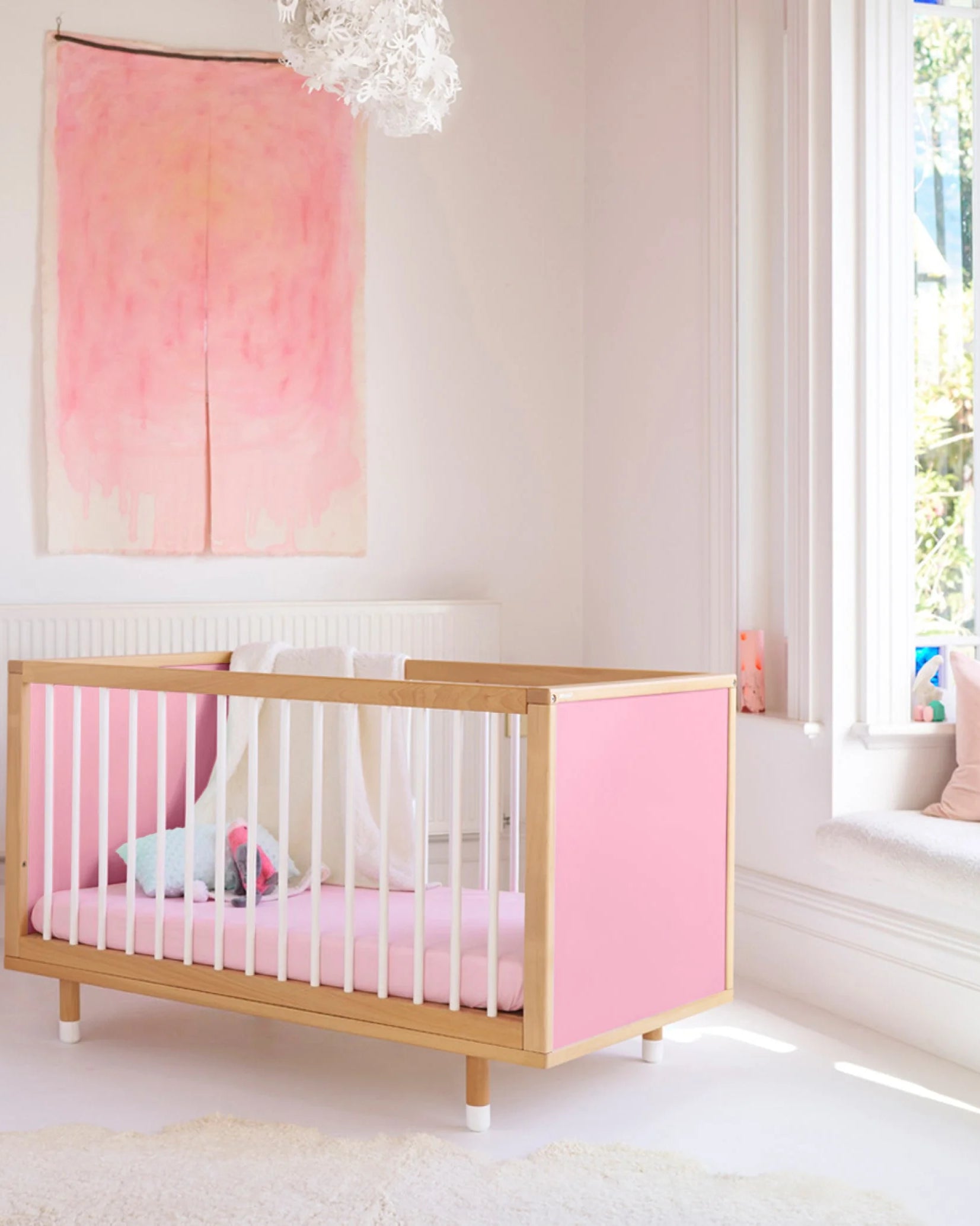 Pink and Red Bold Baby Cot styled in a nursery setting. Pink panels on display.