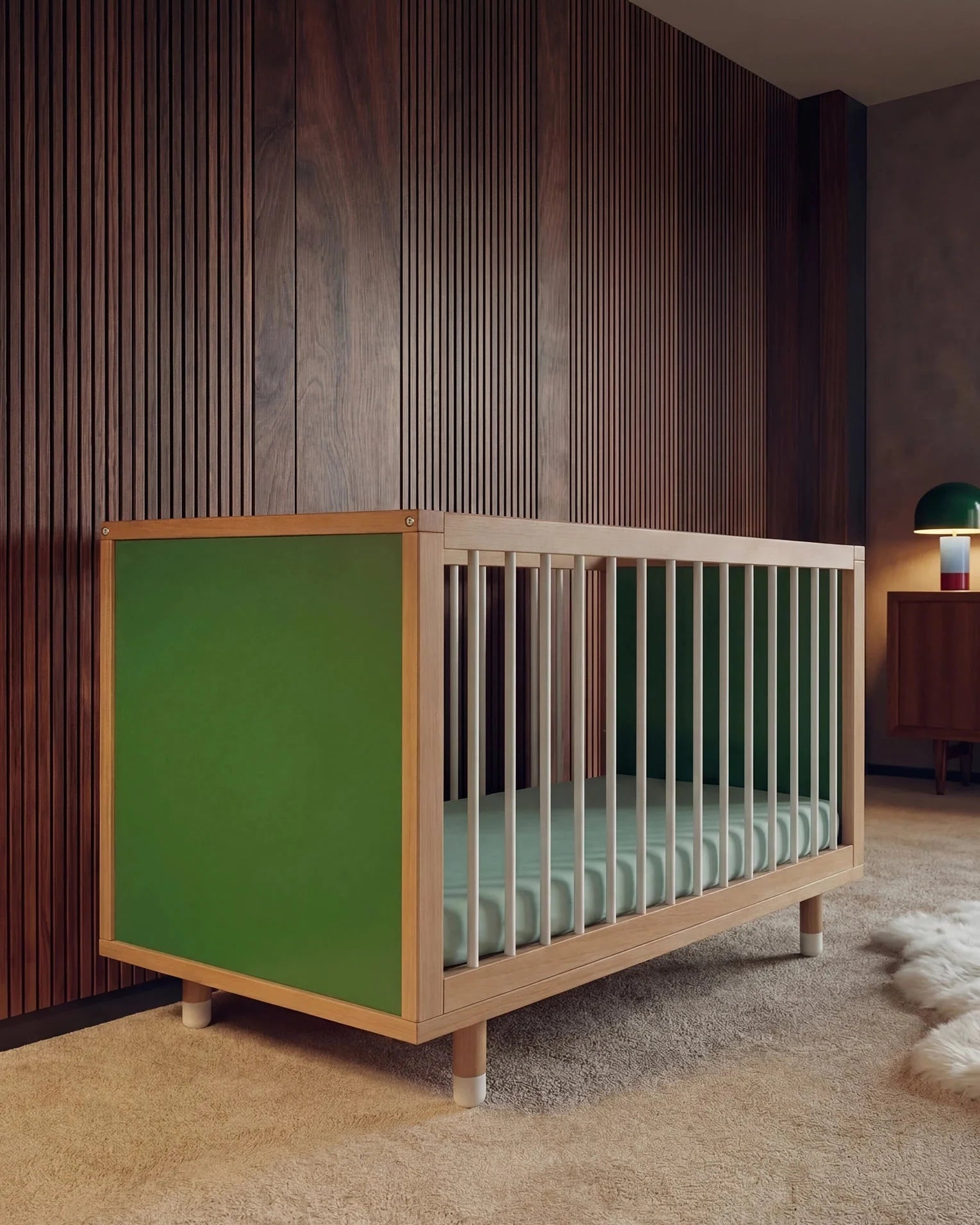 Green and Mint Bold Baby Cot positioned against a timber wall in a stylish nursery.