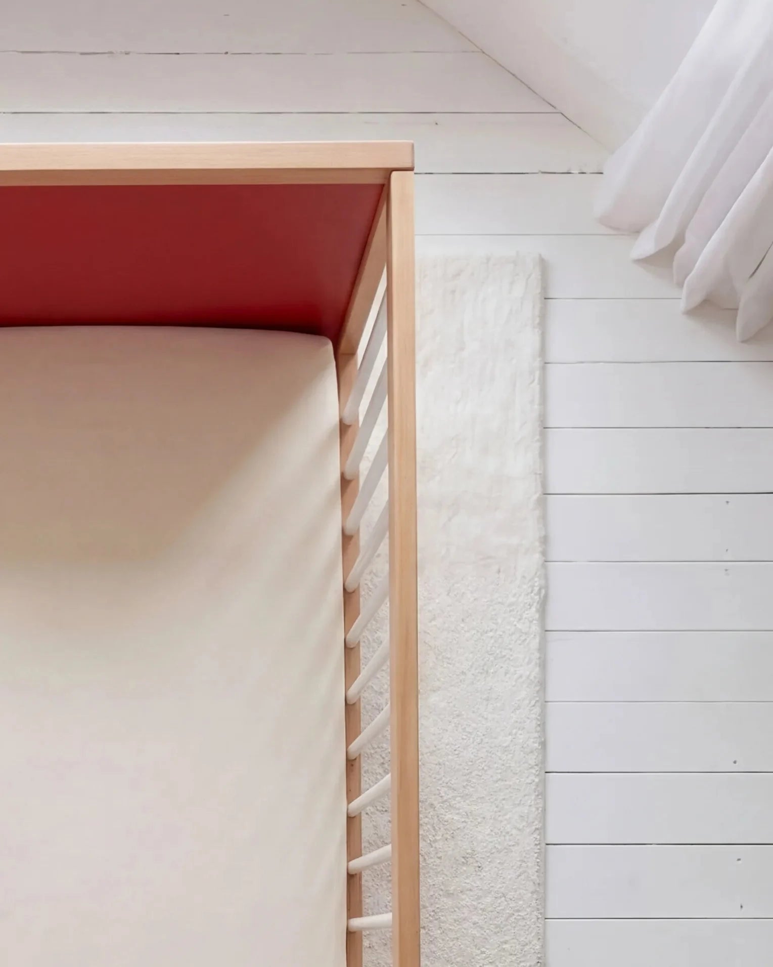 Overhead view of the Pink and Red Bold Baby Cot. Red panel on display.