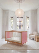 Bold Baby Cot in Pink and Red colourway, front three-quarter view showing the pink panel