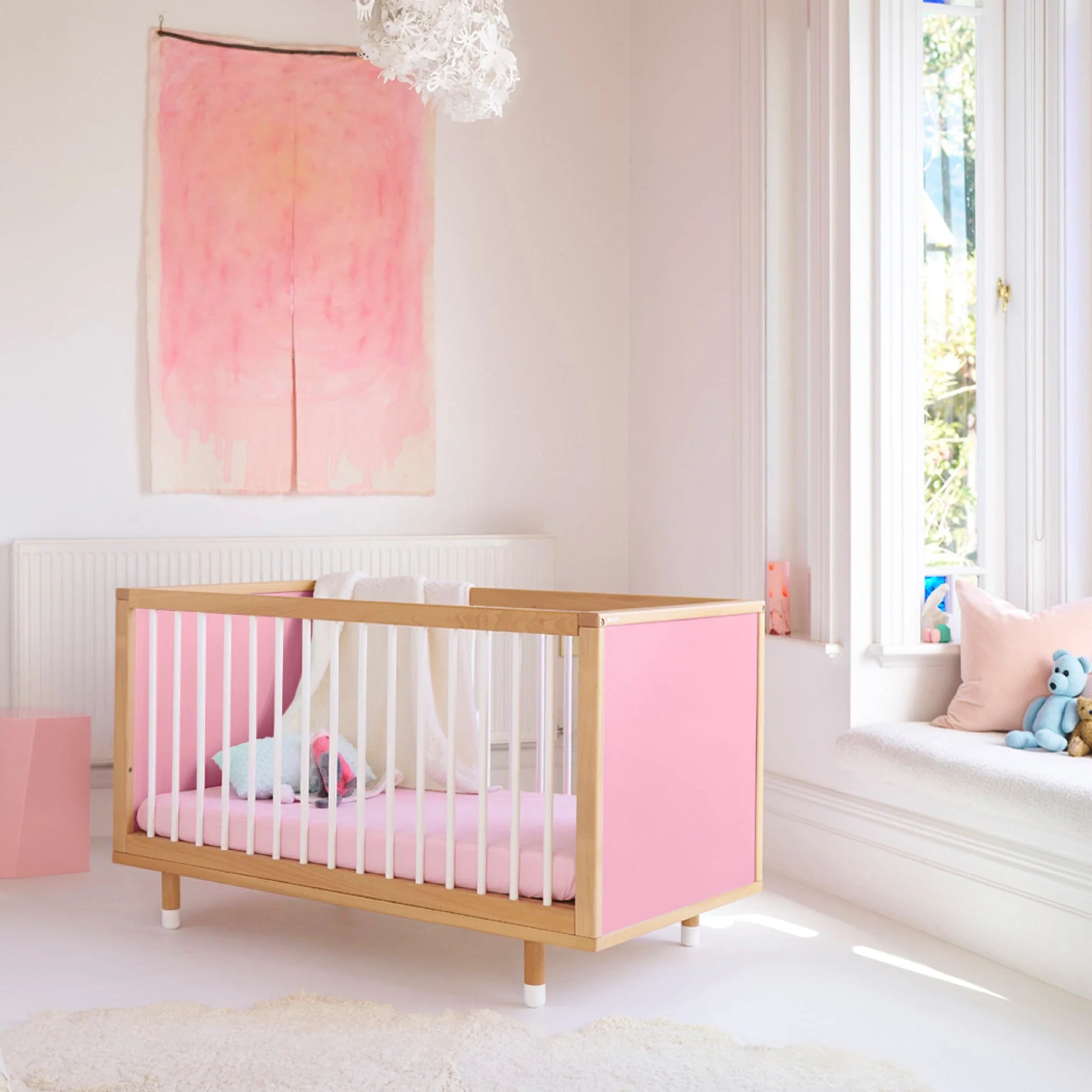 Pink and Red Bold Baby Cot styled in a nursery setting. Pink panels on display.