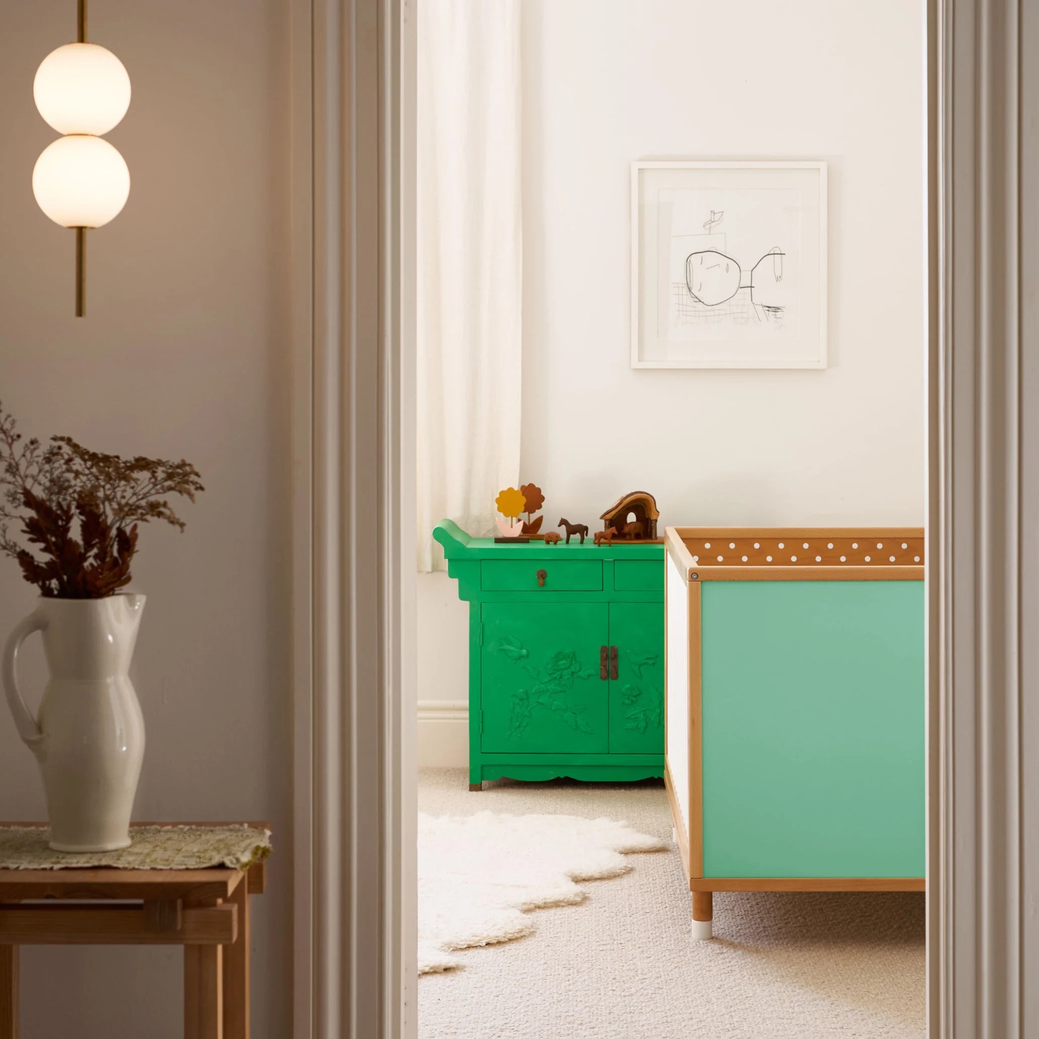 Teal and polkadot panels of the Bold Baby Cot shown in a styled nursery. 