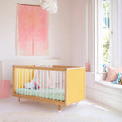 Yellow panels of the Bold Baby Cot shown from a side angle
