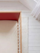 Overhead view of the Pink and Red Bold Baby Cot. Red panel on display.