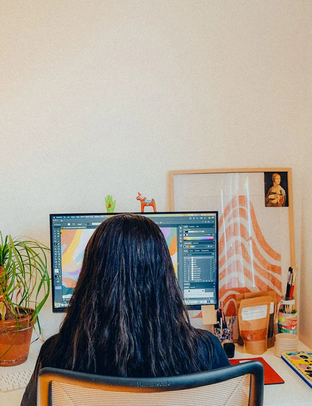 Person sitting at a desk with two computer monitors, surrounded by decor items.