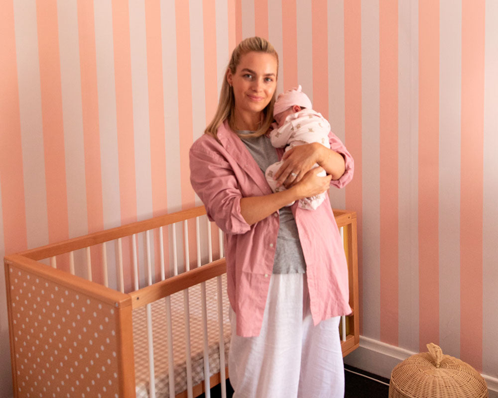 A woman stand with a baby in a colourful nursery