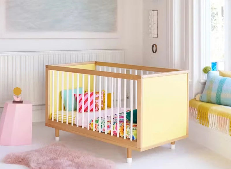 A yellow cot in a beautifully styled nursery